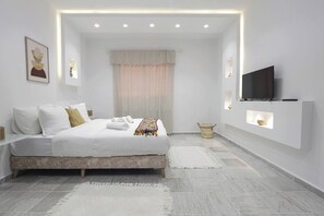 Une chambre à coucher moderne, équipée d’un lit, de tables de chevet, d’un téléviseur et d’étagères intégrées.