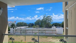 Ein Balkon mit Blick auf Gebäude und Bäume, einem klaren Himmel und ein entferntes Gewässer.