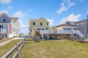 A row of residential houses with a grassy yard, wooden fences, and a clear sky.
