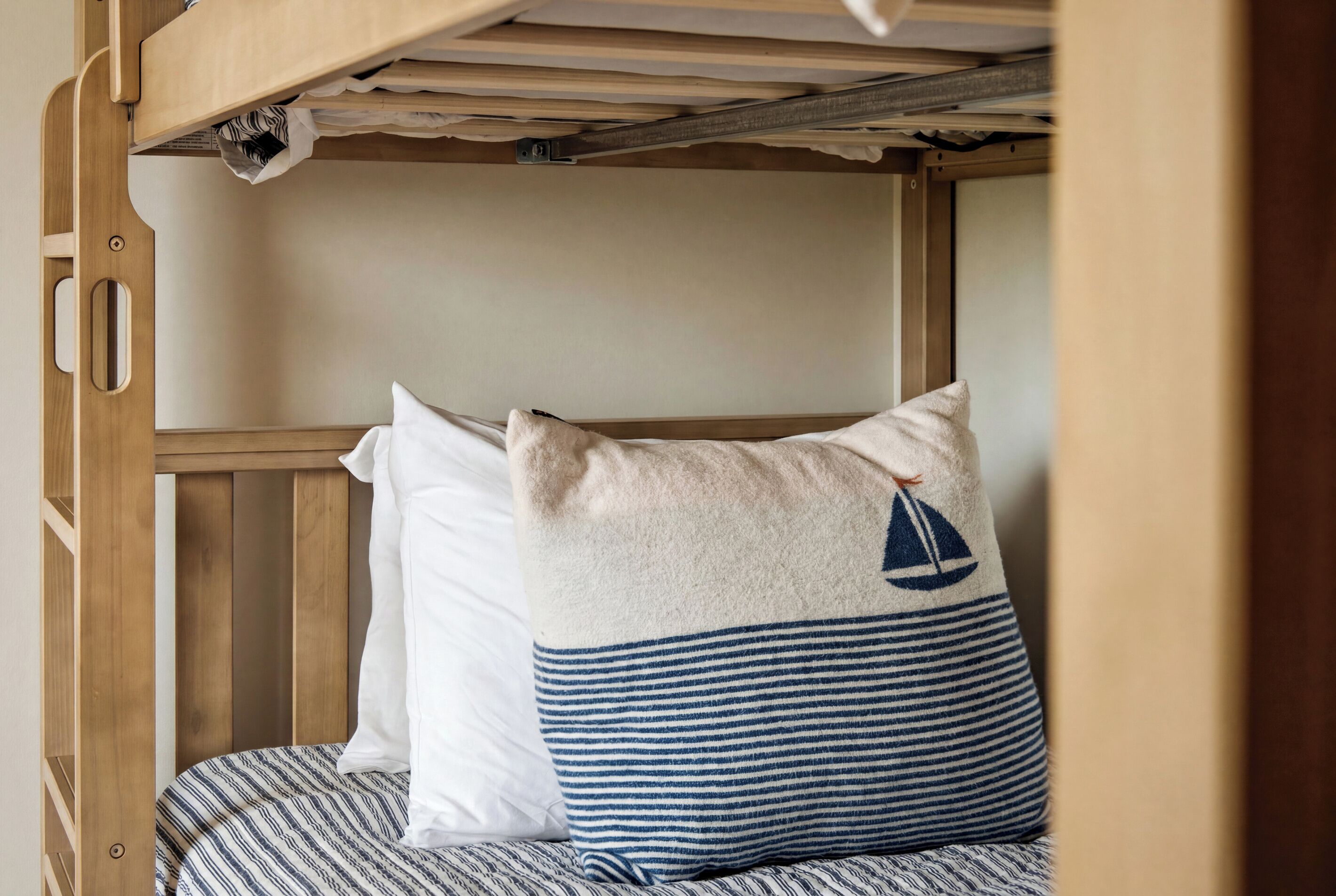 A bunk bed with a striped pillow and a plain pillow.