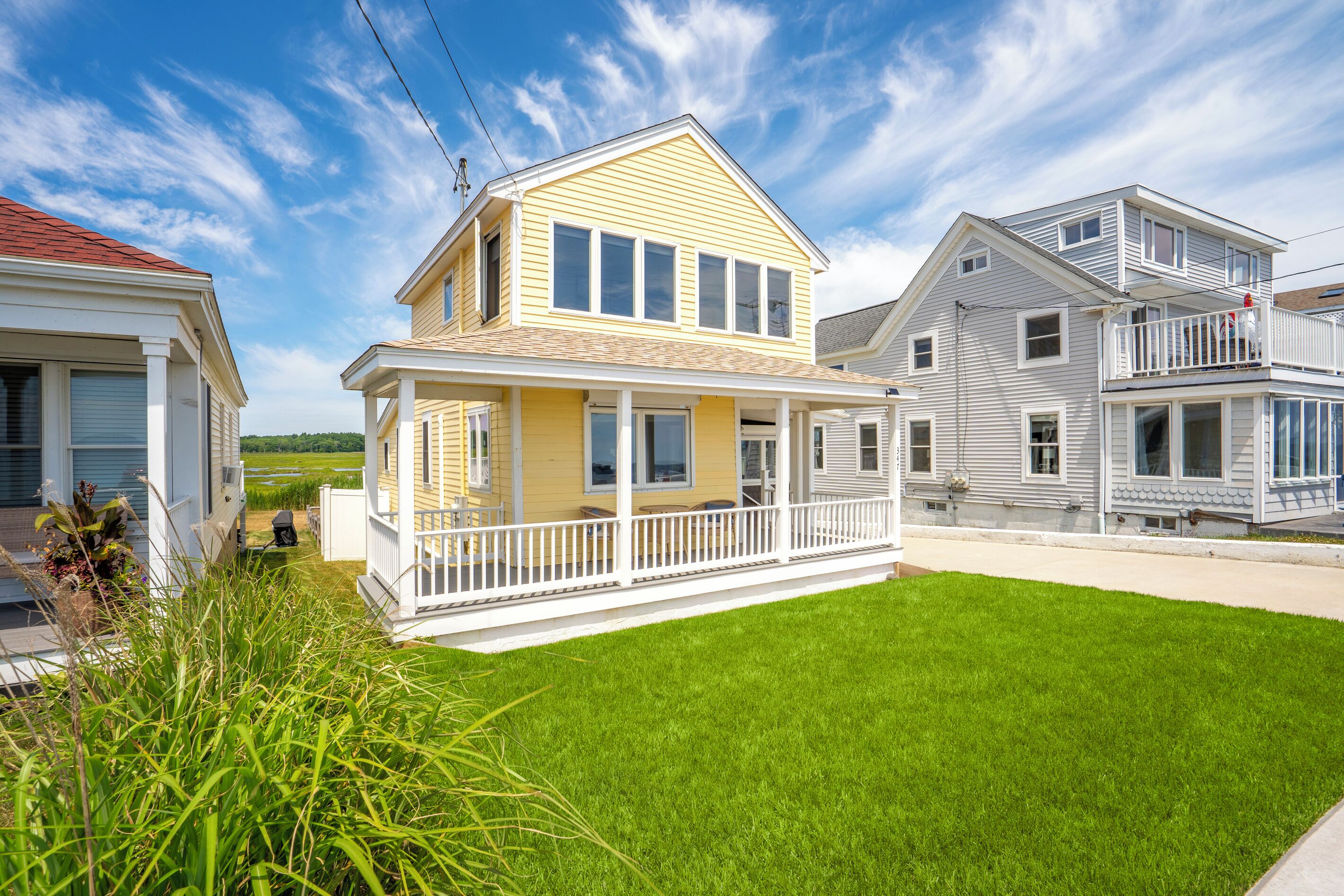 A two-story house with a front porch, a well-maintained lawn, and a clear blue sky.