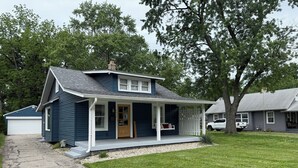 Een gelijkvloers huis met een veranda, een garage en een verzorgd gazon.