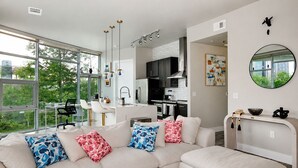 A modern living room with a beige sofa, a dining area, and a kitchen.