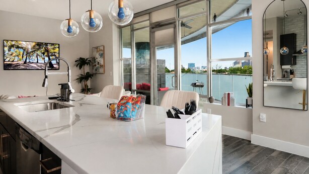 A modern kitchen with a large island, a dining area with a view, and a large window overlooking a cityscape.