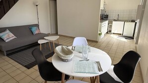 Un espacio habitable moderno con comedor, sofá y cocina al fondo.