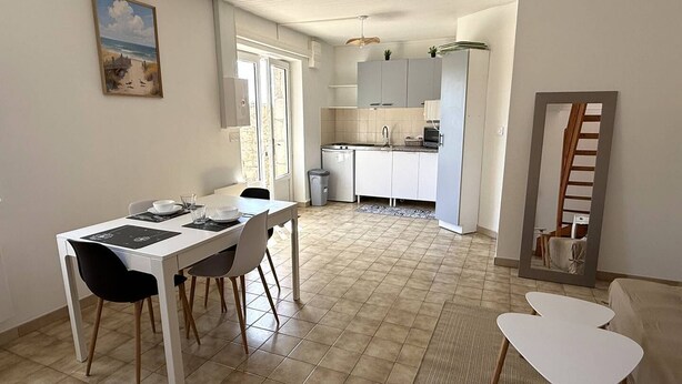 A dining area with a table, chairs, and a kitchen in the background. - NEW LISTING, Domaine de KER-PAULT, between St Cast and Matignon, 2-bedroom apartment 5 minutes... (MATIGNON)