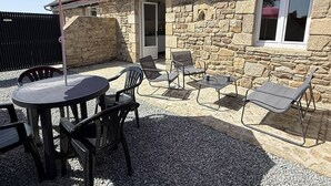 A stone building with a patio area featuring a round table, four chairs, and a large umbrella. - NEW LISTING, Domaine de KER-PAULT, between St Cast and Matignon, 2-bedroom apartment 5 minutes... (MATIGNON)
