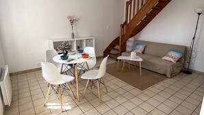 Ein Wohnzimmer mit Esstisch, Stühlen, einer Couch, einer Treppe und einer Heizung.