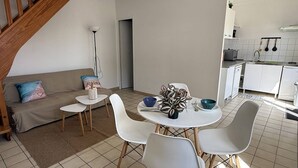 Eine moderne Küche mit weißen Schränken, einem Essbereich mit rundem Tisch und vier Stühlen sowie einer Treppe, die zu einer oberen Ebene führt.