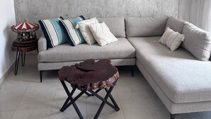 Un salon comprenant un canapé d’angle, une table basse en bois, un carrousel et une œuvre d’art représentant un vélo, accrochée au mur.