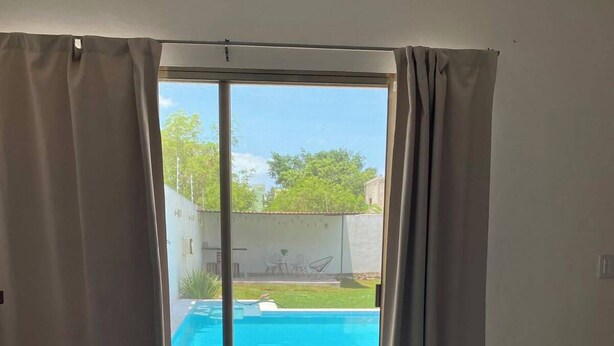 Une chambre avec un lit, une vue sur une piscine et une porte-fenêtre coulissante.