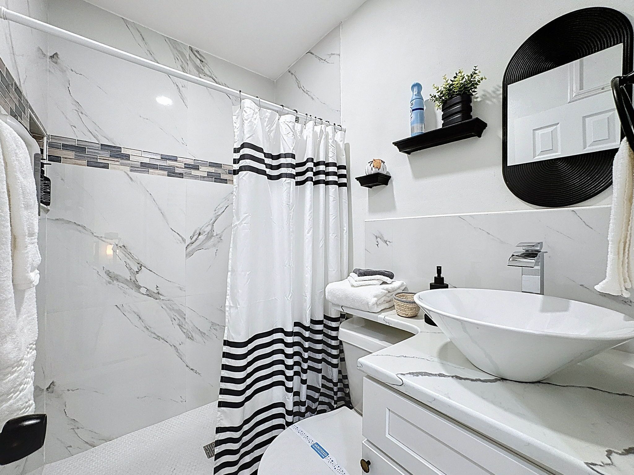 Ein Badezimmer mit weißem Waschbecken, einem Spiegel, einer Duschvorhang und einem Handtuchhalter.
