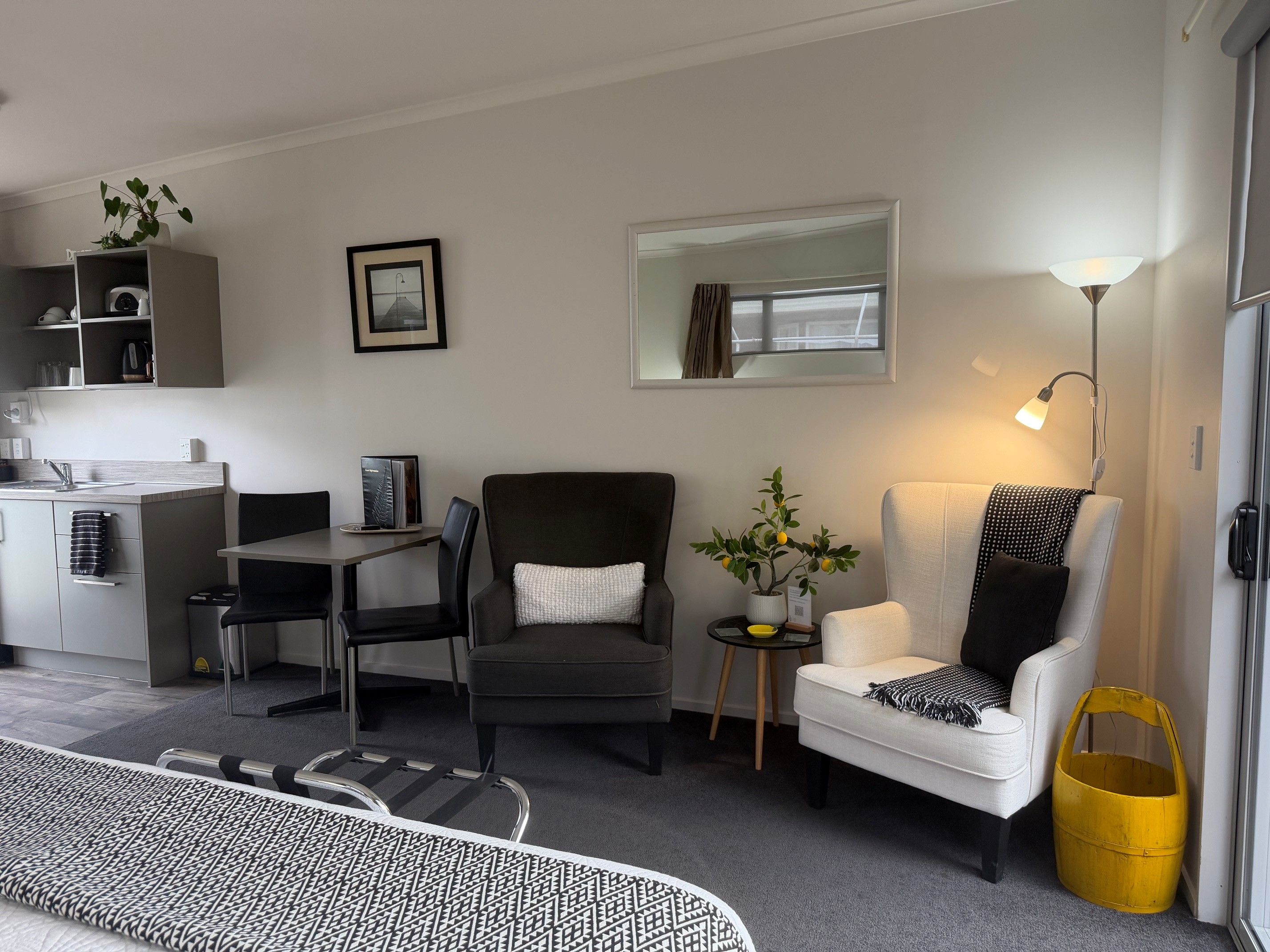 A modern living room with a sofa, armchair, and a dining area with a table and chairs.