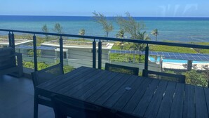 A balcony with a view of the ocean, solar panels, and a pool.