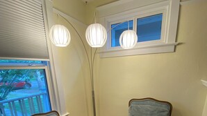 A room with two upholstered chairs, a small table, and a window with blinds. - Charming home in Lethbridge with piano, beautiful neighborhood, central location (Lethbridge)