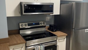 A kitchen with stainless steel appliances, white cabinets, and a wooden countertop. - Charming home in Lethbridge with piano, beautiful neighborhood, central location (Lethbridge)