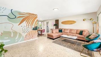A modern living room with a sofa, chairs, a coffee table, and a decorative wall mural.