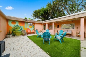 A backyard with a patio area, outdoor seating, and a mural on the wall.