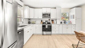 A modern kitchen with white cabinets, stainless steel appliances, and a wooden floor. - Villa Oasis • 1 Block to Beach + Downtown Cocoa Beach (Cocoa Beach)