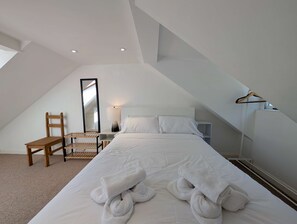 A bedroom with a bed, a chair, a mirror, a lamp, and a hanging coat rack. - Two bed Flat Near King s Cross St Pancras (London)