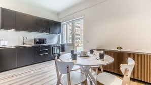A modern kitchen with dark cabinets, a round dining table, and white chairs. - Alessandrino, La Dolce Via del Campo (Rome)