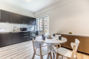 Une cuisine moderne avec des meubles de couleur sombre, une table de salle à manger ronde et des chaises blanches.
