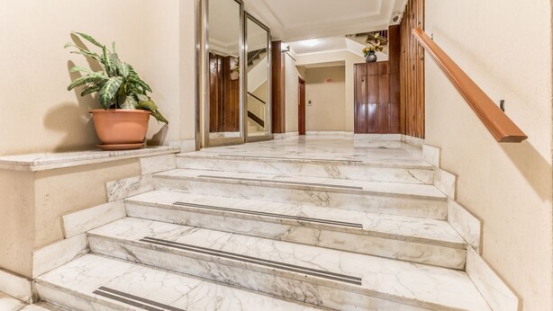 A marble staircase leading to a landing with a potted plant on the left. - Alessandrino, La Dolce Via del Campo (Rome)
