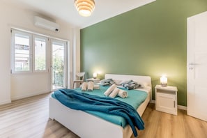Une chambre à coucher comprenant un lit, des tables de chevet, une fenêtre et un appareil de climatisation.