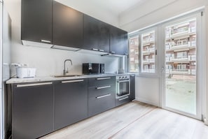 Une cuisine moderne avec des meubles de couleur sombre, un four à micro-ondes, un évier et un four traditionnel.
