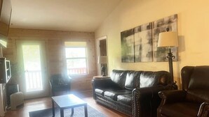 Una sala de estar con un sofá, una mesa de centro, una lámpara y un cuadro en la pared.