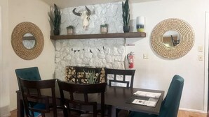 Un comedor con pared de piedra, dos espejos redondos, una mesa de madera y sillas.