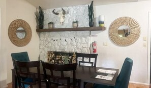 A dining area with a stone wall, two round mirrors, a wooden table, and chairs.