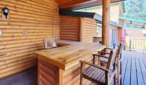 Een houten blokhut met een houten tafel en stoelen, een hanglamp en uitzicht op de omgeving.