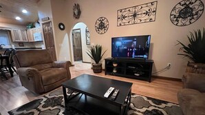 Ein Wohnzimmer mit Fernseher, einer Couch, einem Couchtisch und Wanddekoration.