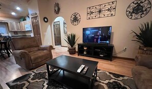 Ein Wohnzimmer mit Fernseher, einer Couch, einem Couchtisch und Wanddekoration.