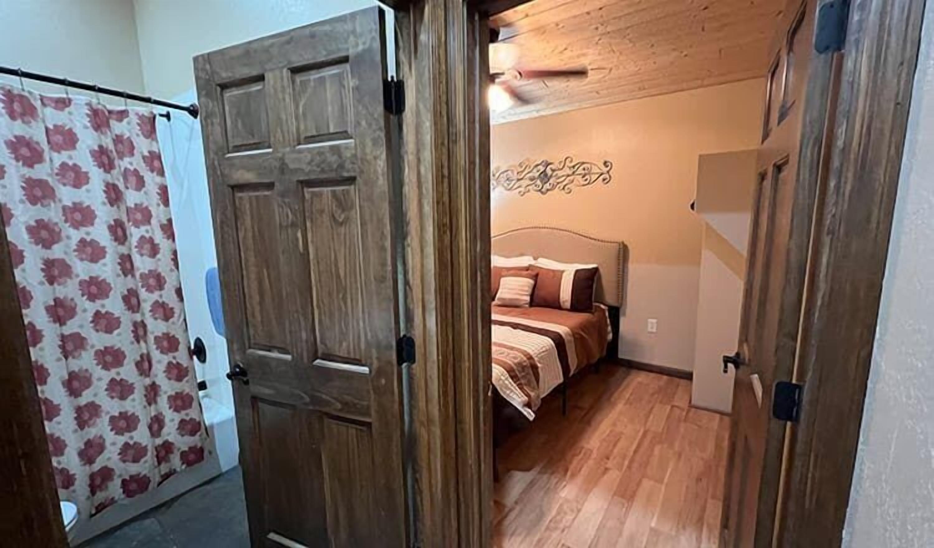 Une chambre à coucher avec un lit, une porte en bois et un rideau à motifs floraux.