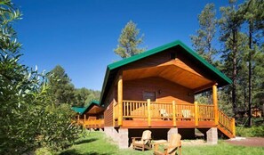Eine Holzhütte mit Veranda und einem draußen stehenden Esstisch.