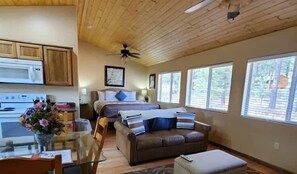 Ein Zimmer mit einer Küchenzeile, einem Bett, einer Couch und großen Fenstern.