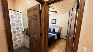 Ein Schlafzimmer mit Holztür, einem Bett mit Kopfteil, einer Duschvorhang und einem Deckenventilator.