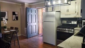 Una cocina compacta con refrigerador, estufa y gabinetes blancos.