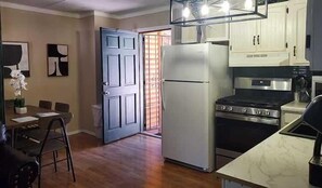 A compact kitchen with a refrigerator, stove, and white cabinets.
