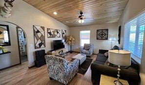 A living room with a TV, sofa, armchair, and decorative wall art. - Tranquil Springs Escape #94 (Greer)