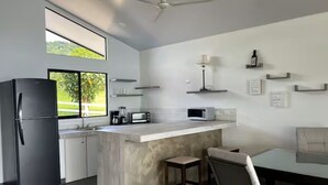 A modern kitchen with a central island, a refrigerator, a microwave, and a dining area with a table and chairs. - Lake view Cattle Ranch Villa (Río Chiquito)
