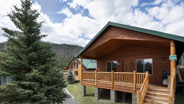 Een houten chalet met een veranda, een trap en een grindpad.