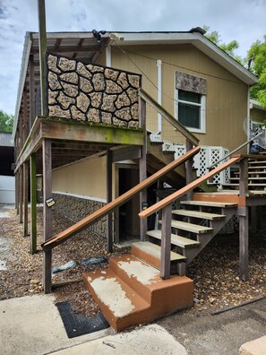Ein zweigeschossiges Haus mit einer Steinfassade, Holztreppe und einer kleinen Veranda.