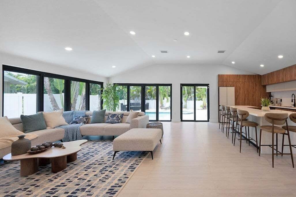A modern living room with a sofa, coffee table, and a dining area with bar stools.