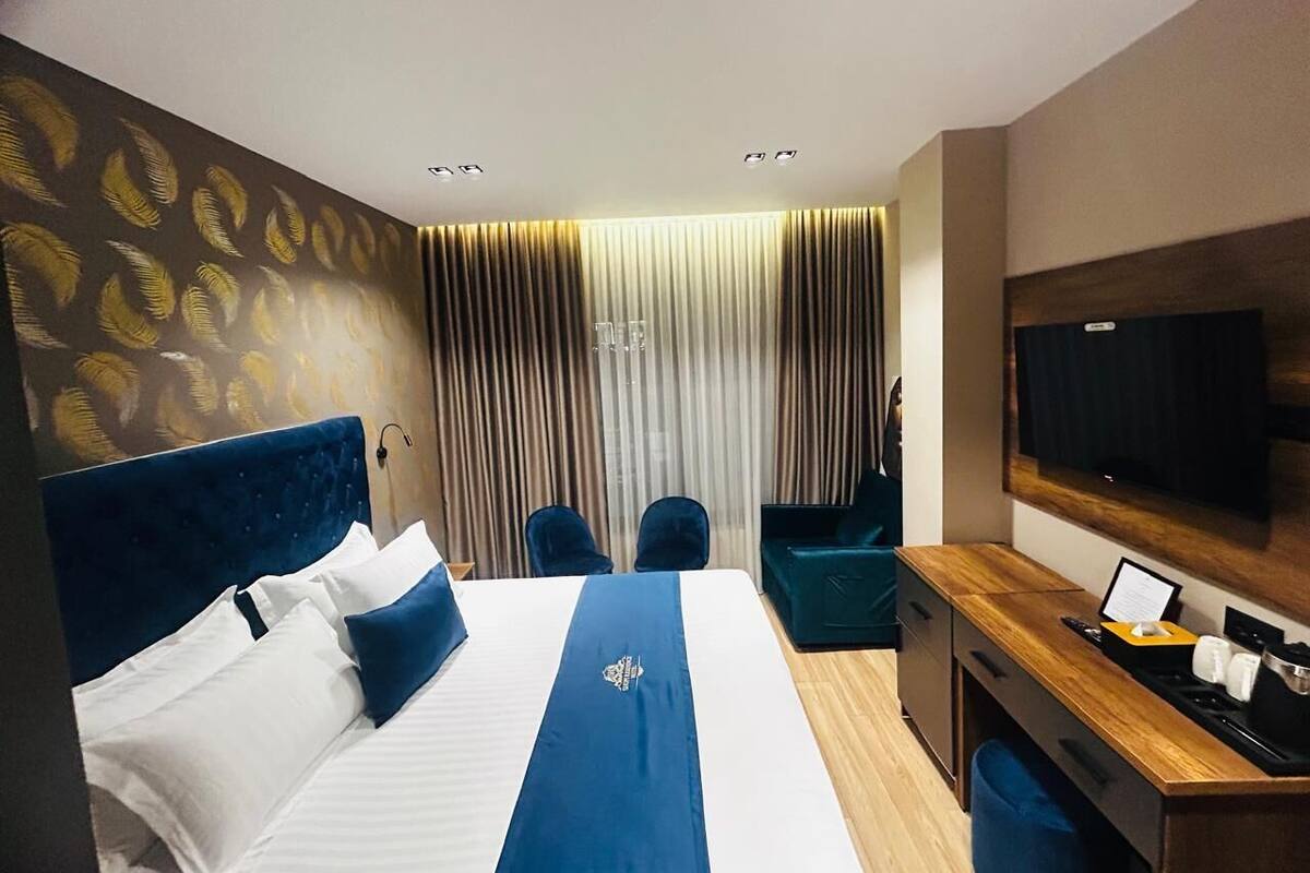A hotel room with a bed, a desk, a chair, a television, and a curtain.