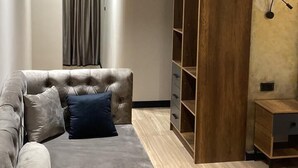 A modern living room with a sectional sofa, built-in shelving, and a wooden accent wall. - Hotel Shopi Residence (Elbasan)