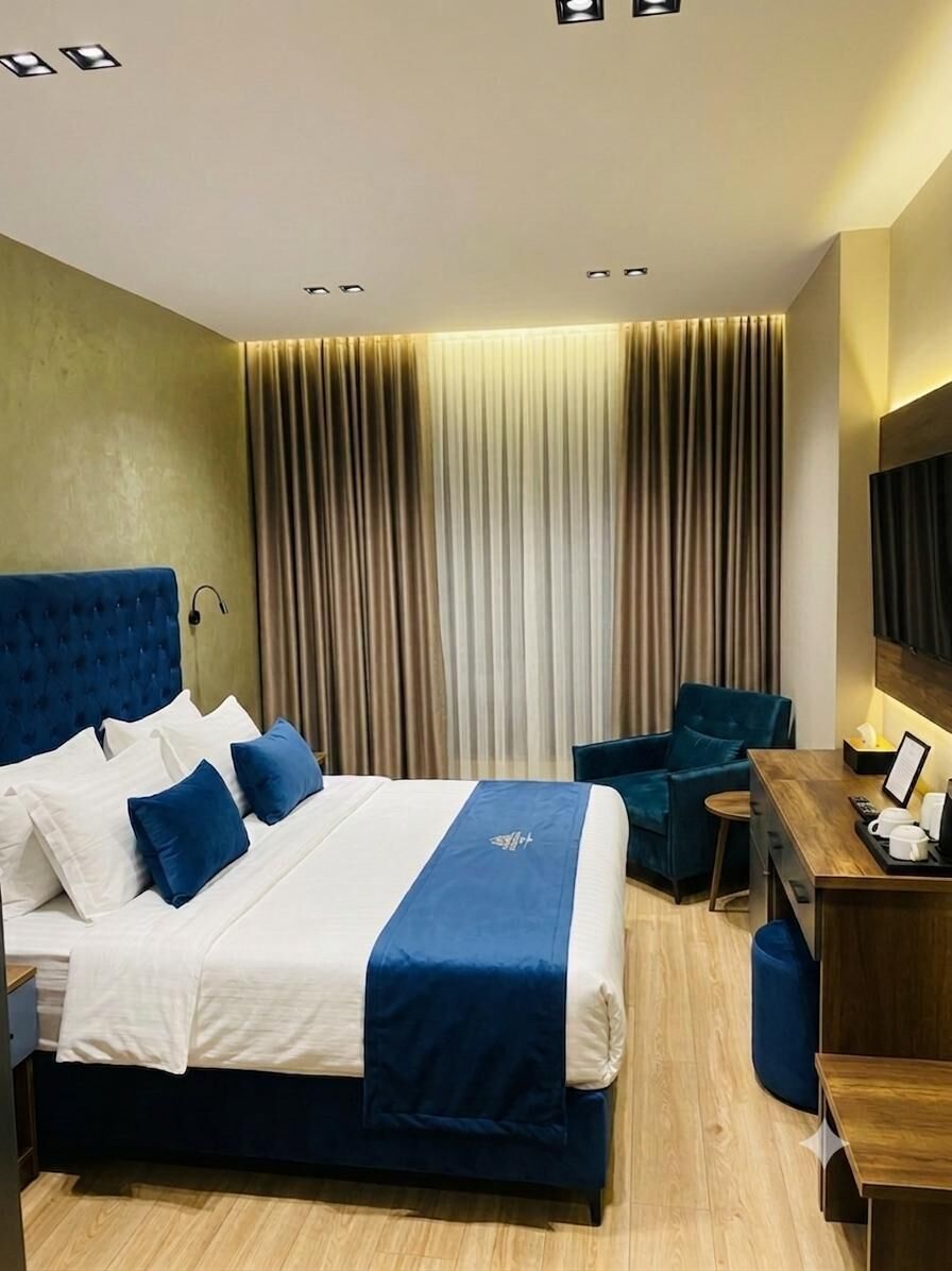 A hotel room with a large bed, a desk, a chair, and a TV.