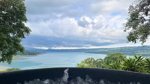 A hot tub with a view of a lake and surrounding landscape. - Top View Cottage in Lake Arenal (Río Chiquito)
